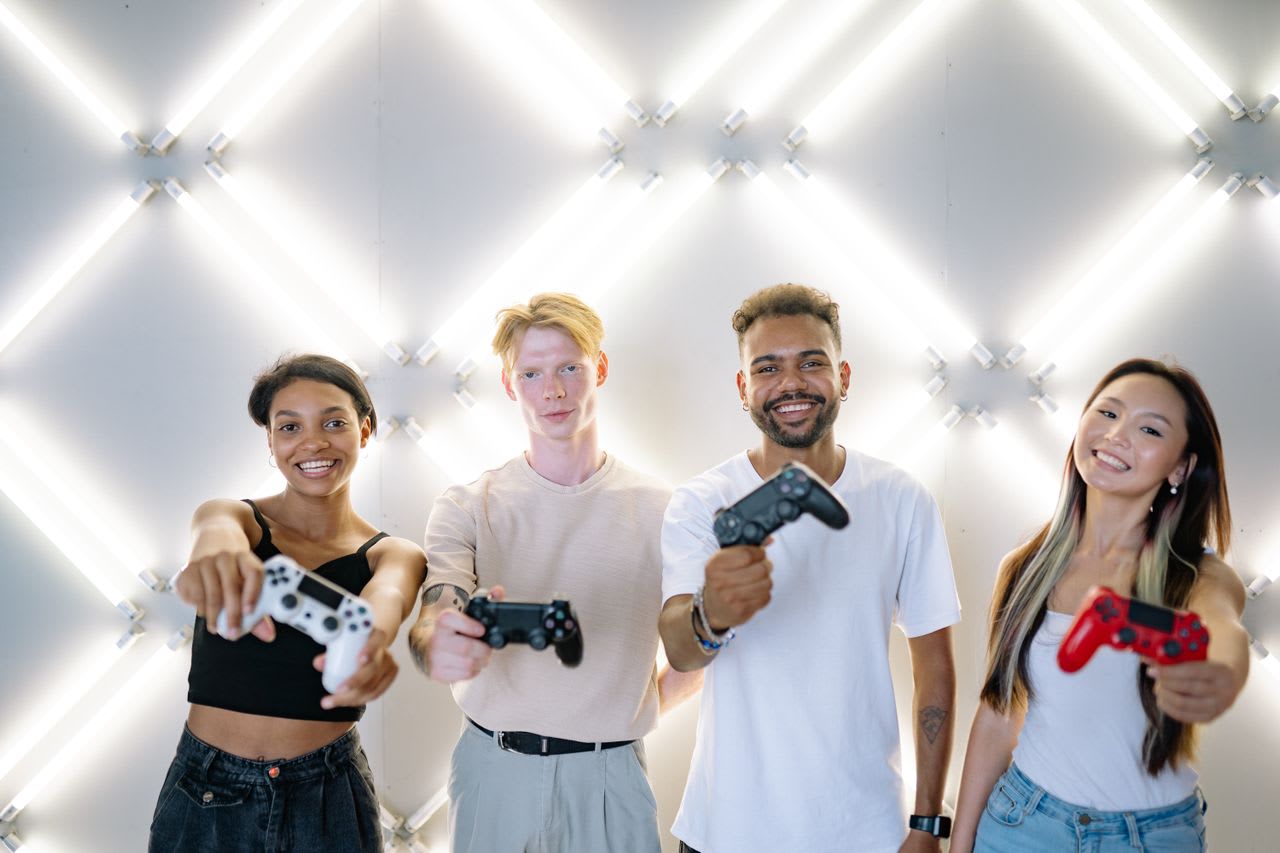 https://www.pexels.com/photo/group-of-friends-smiling-while-holding-game-controllers-9068899/