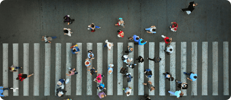 overhead image of people crossing at a busy crosswalk, walking in both directions