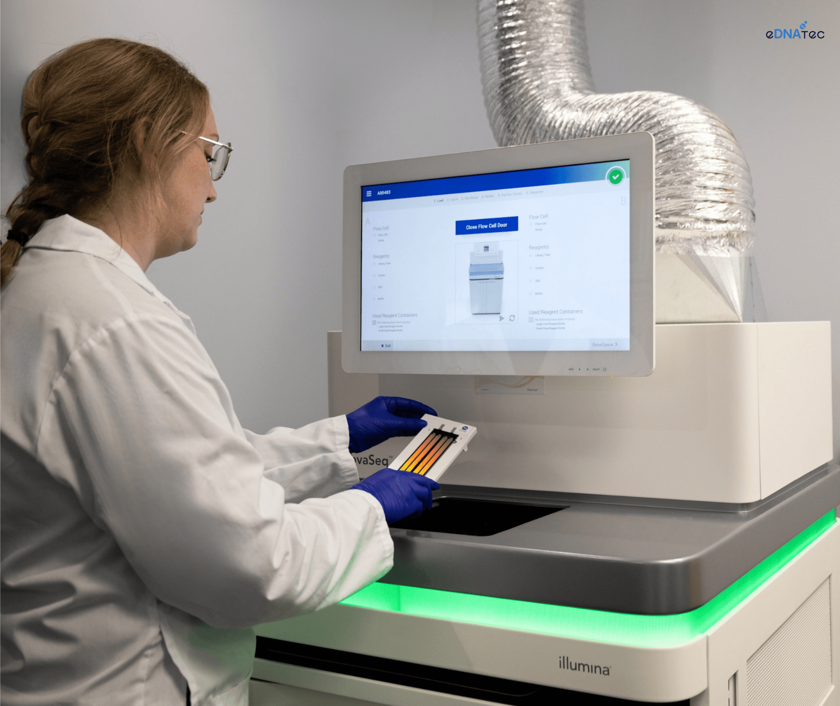 A lab technician operates a NovaSeq machine, preparing a sample for DNA sequencing.