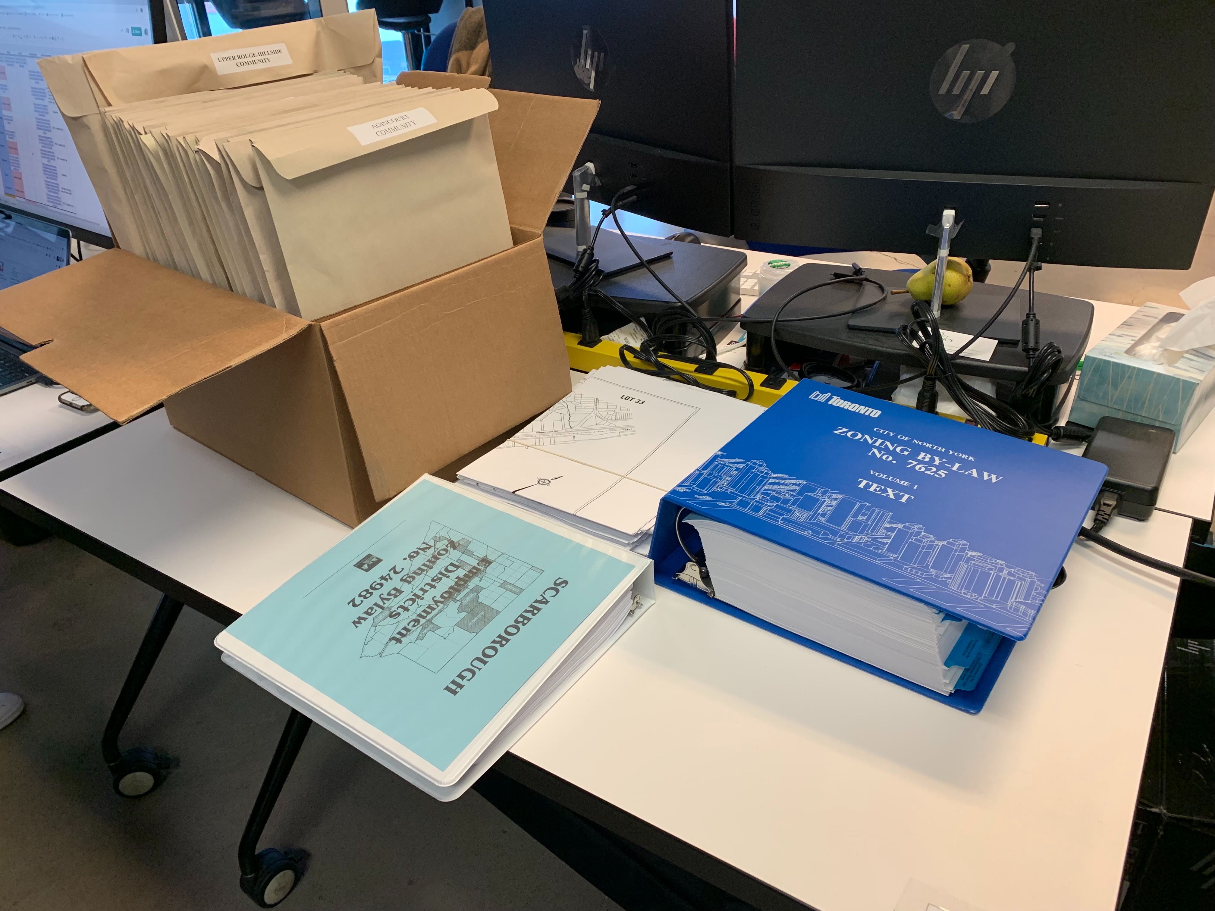 A table with huge binders and folders containing former Toronto zoning by-law information.