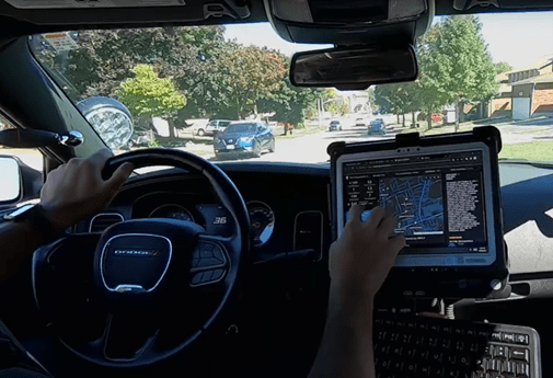  Police officer viewing the dashboard on a laptop during a field check. 