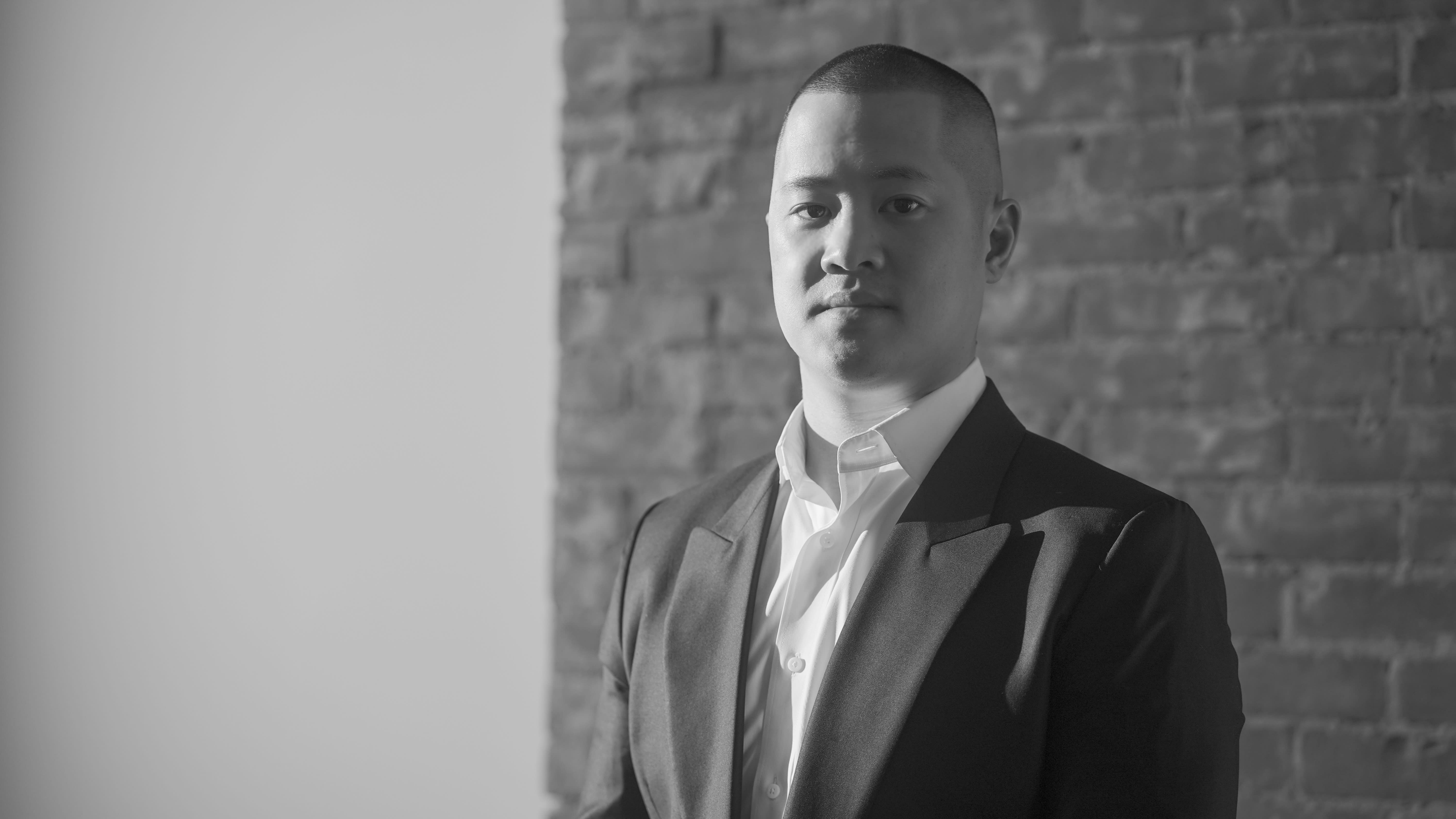 A black and white picture of Aaron Yick in a suit.