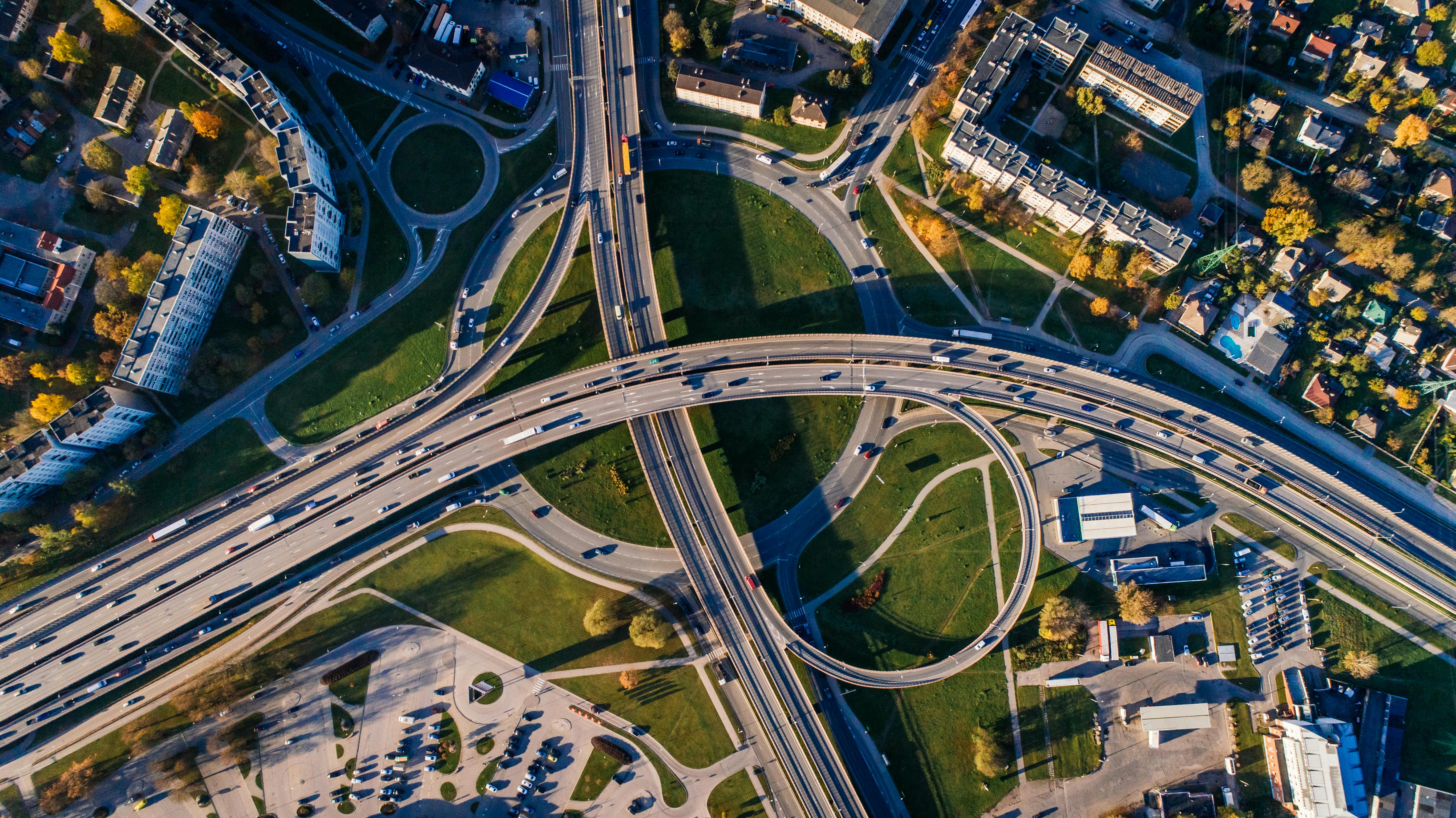 Aerial view of complex highway interchange with multiple levels, loop ramps, and surrounding urban development showing transportation infrastructure and traffic management systems