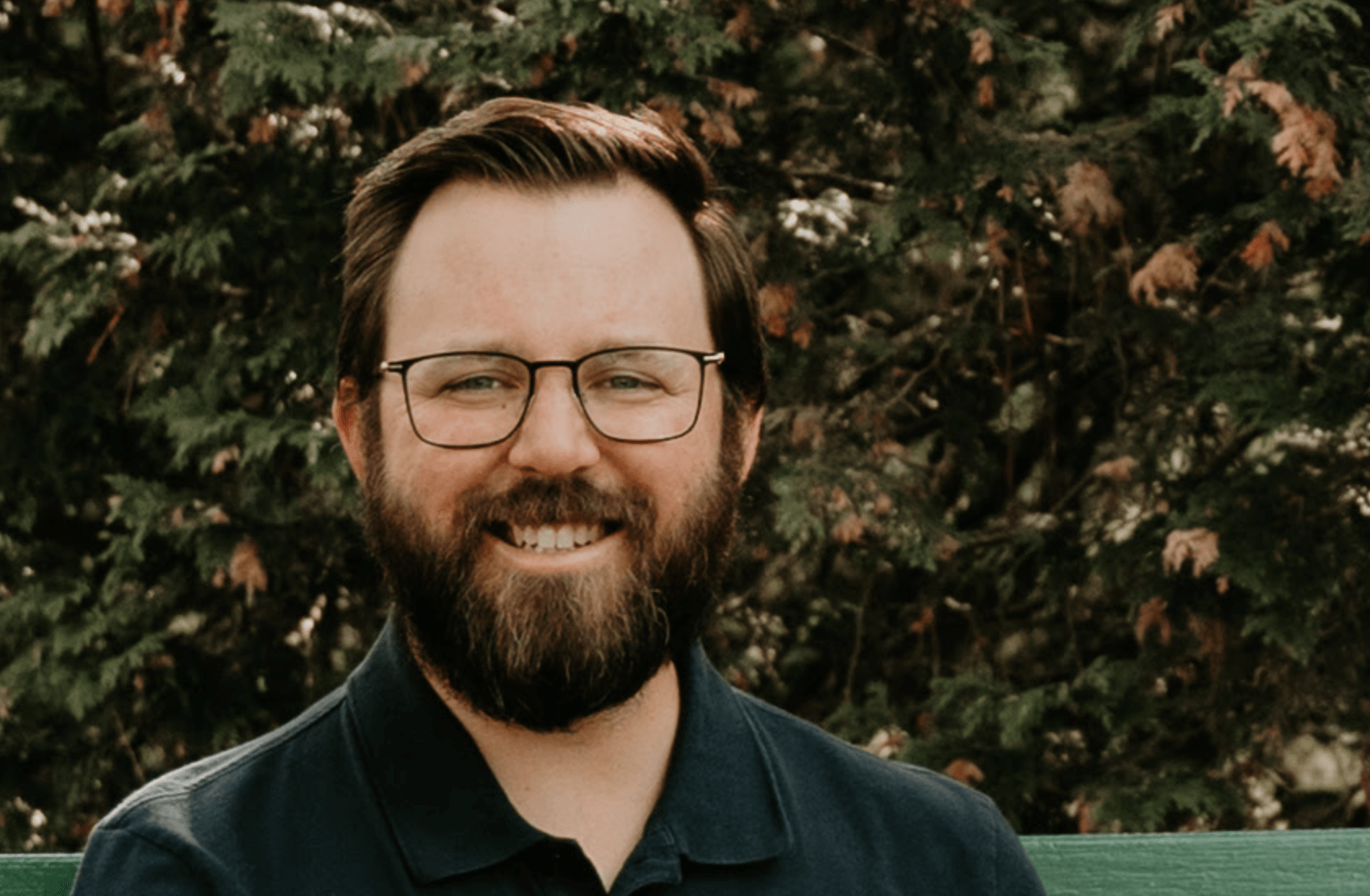 An image of a man with a beard and glasses smiling.