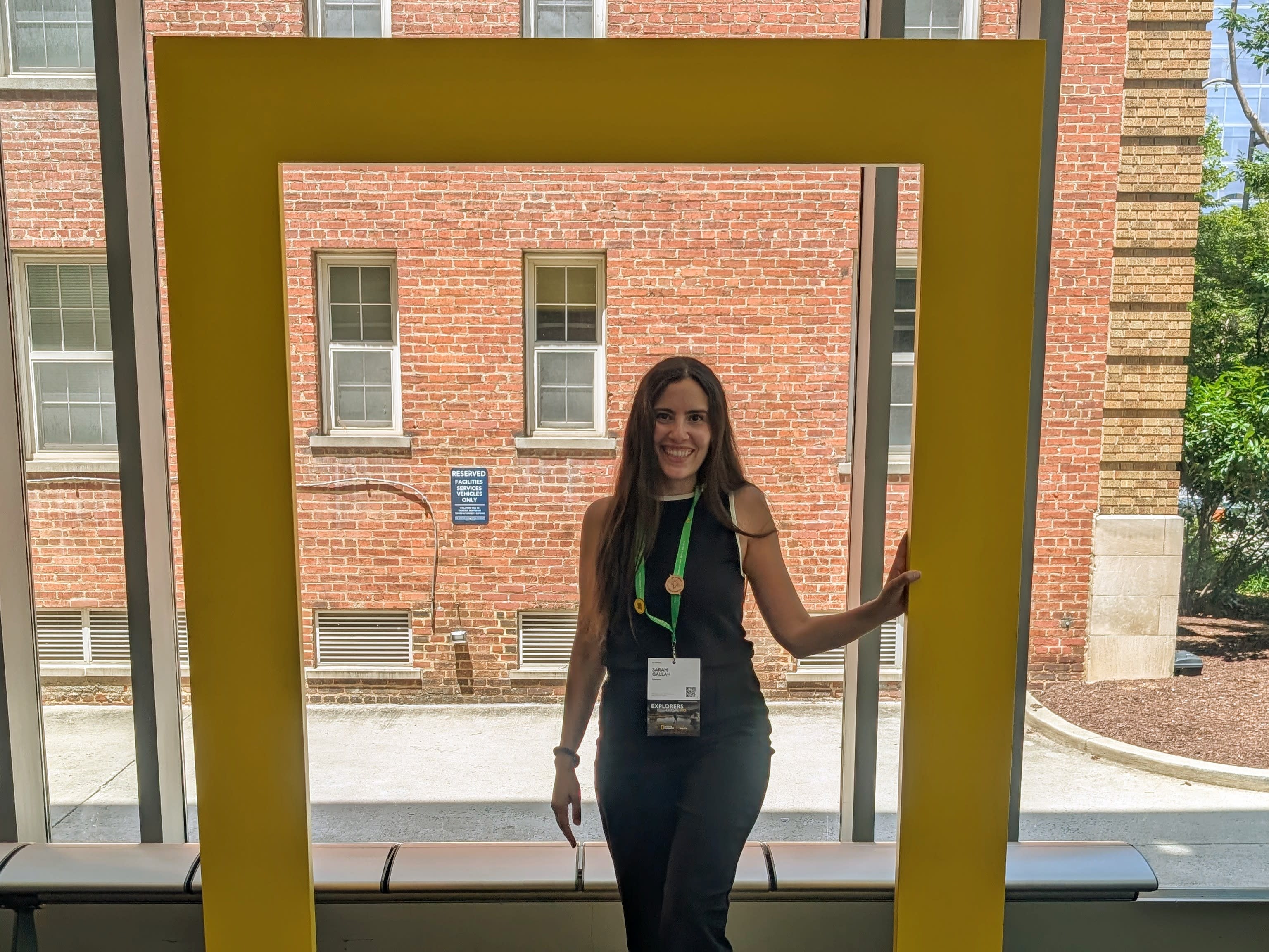 A woman smiling in front of a window inside a school.