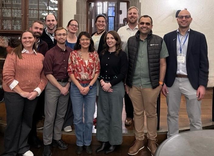 A group of 11 people standing and smiling.