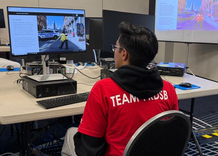 Un élève assis à un ordinateur lors des Olympiades de SIG de Compétences Ontario en mai 2025.