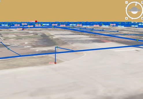Repr&eacute;sentation 3D d&rsquo;un terrain avec des lignes bleues illustrant des conduites souterraines. Des &eacute;tiquettes rouges et jaunes marquent des points sp&eacute;cifiques le long du r&eacute;seau, et une interface de navigation est visible dans le coin sup&eacute;rieur droit.
