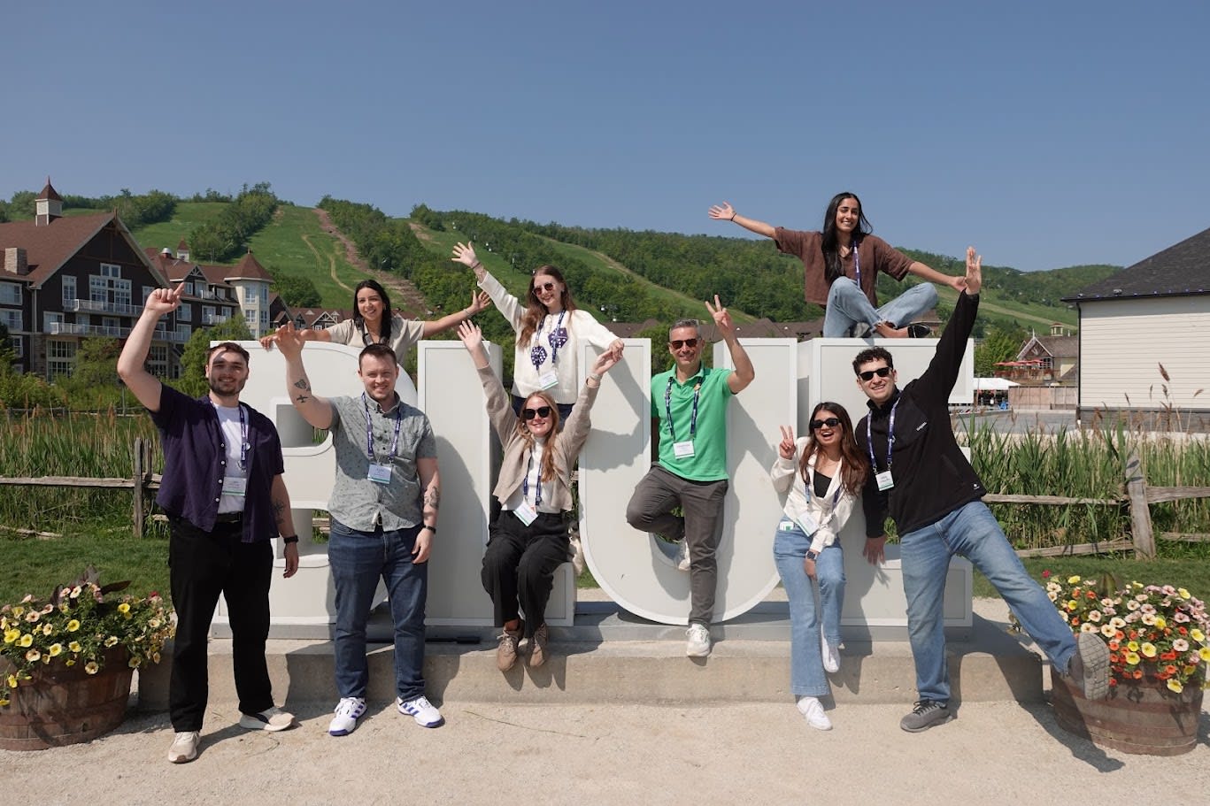 Group of individuals who are part of Esri Canada’s Associate GIS Professional Program in front of a sign and mountain at Blue Mountain, Ontario in June 2025.