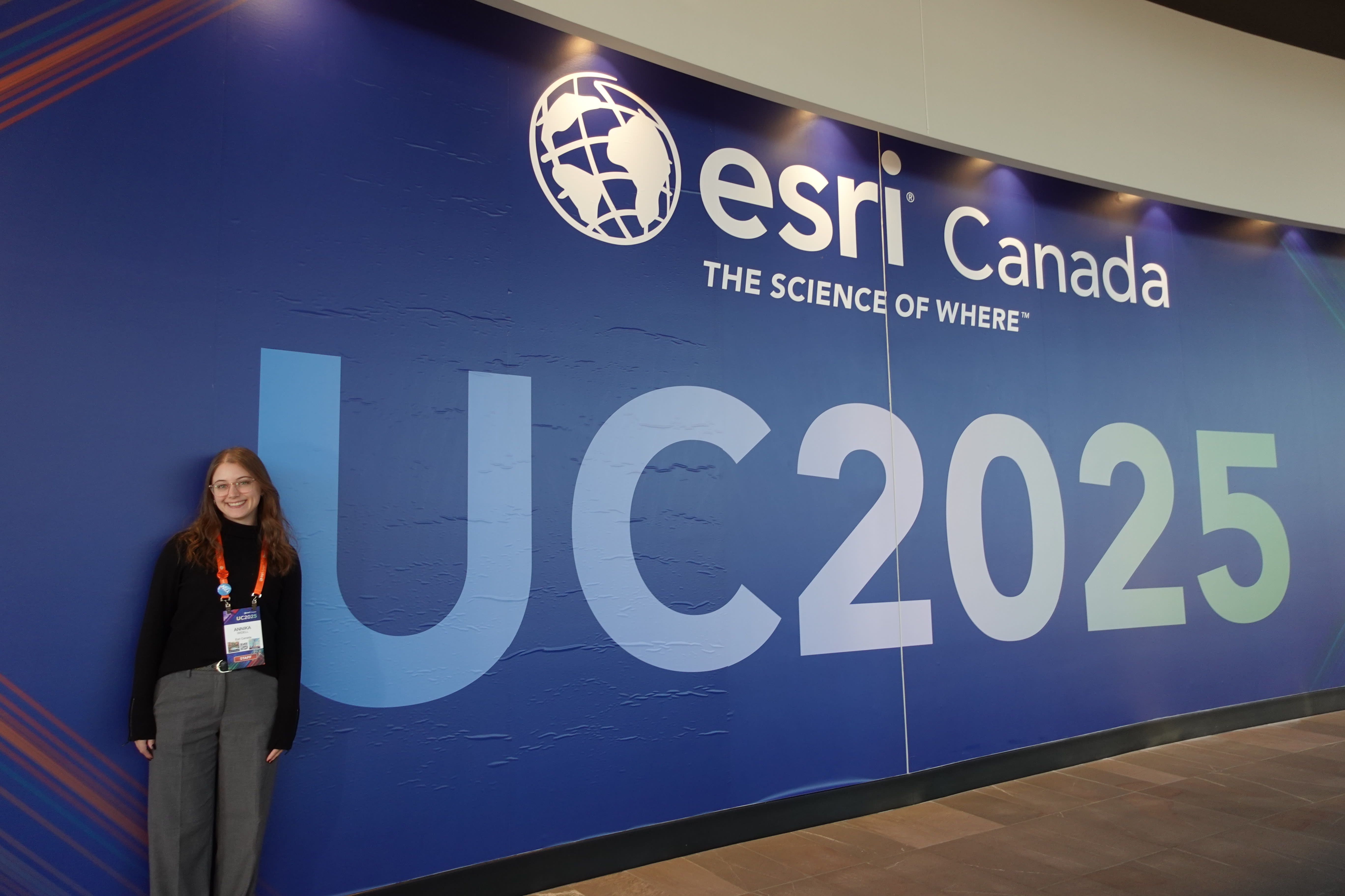 Annika standing in front of a Esri Canada UC2025 sign at the Esri Canada User Conference in Toronto, Ontario in November 2025.