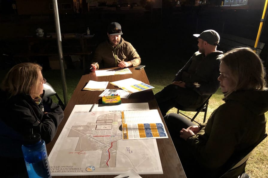 Un groupe de personnes r&eacute;unies autour d&rsquo;une table et utilisant des plans sur papier.