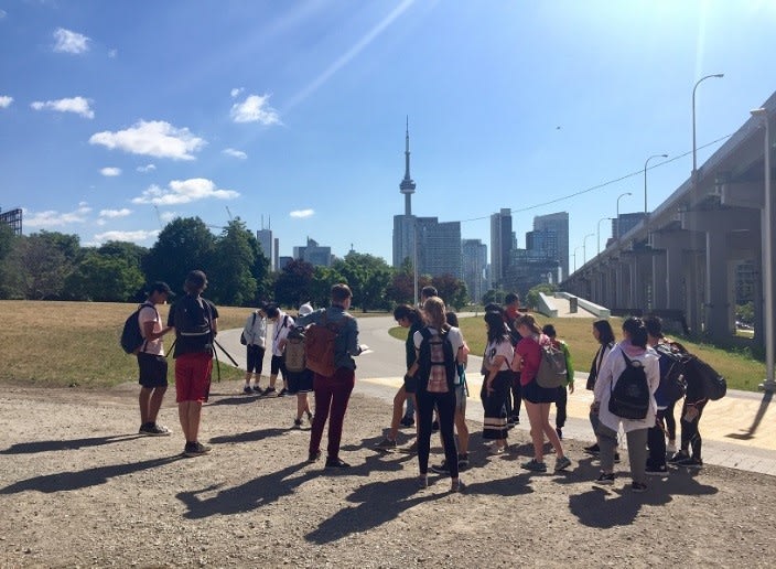 Young people huddled together in an urban area collecting information about their surroundings.