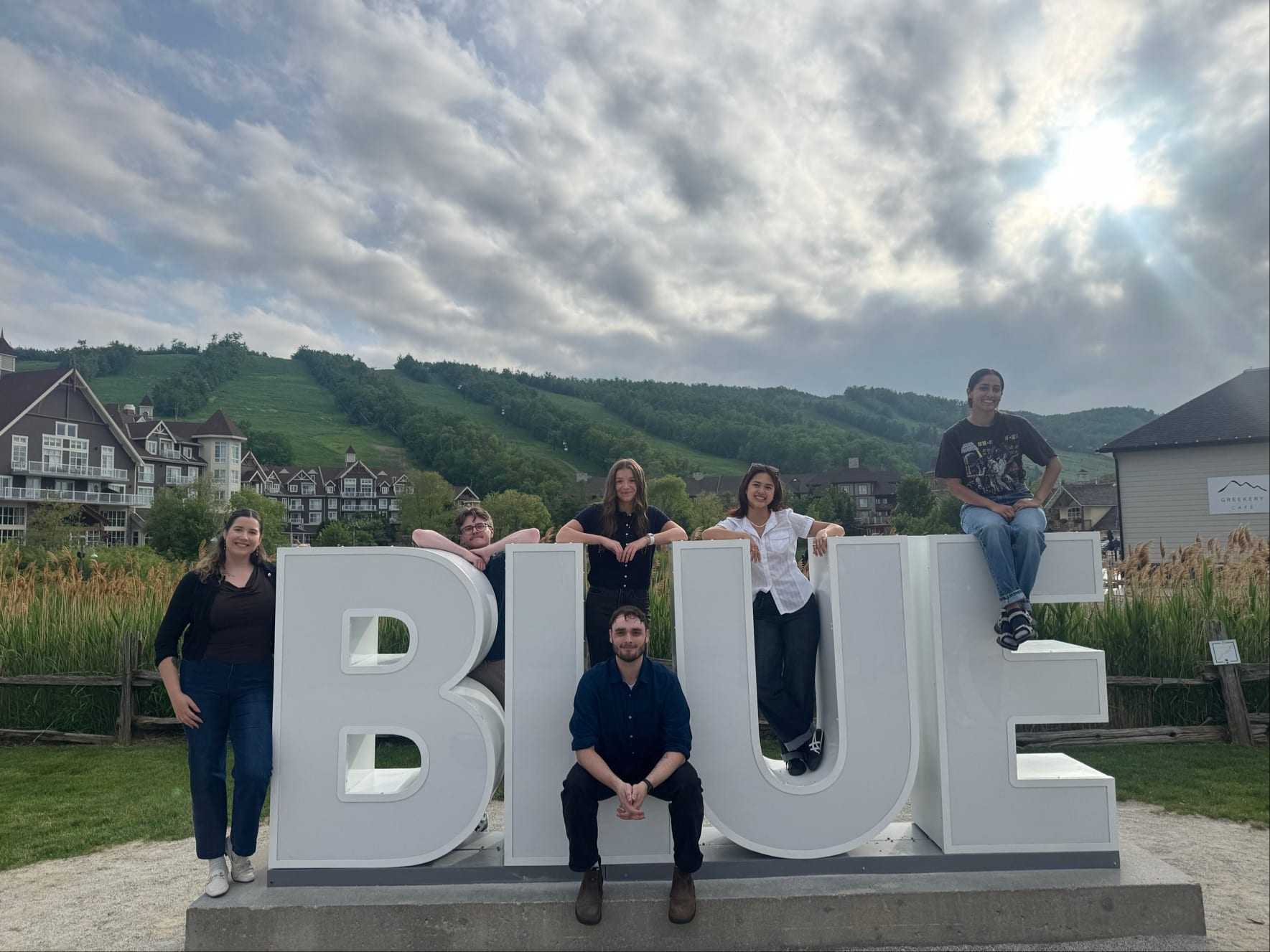Sur fond de ciel nuageux et de colline de ski verdoyante, six participants du programme Associate GIS Professional d’Esri Canada posent parmi les lettres géantes du mot « BLUE », installées comme une sculpture. Une personne est appuyée contre la lettre « B », une autre est assise au bas de la lettre « L », et ainsi de suite.