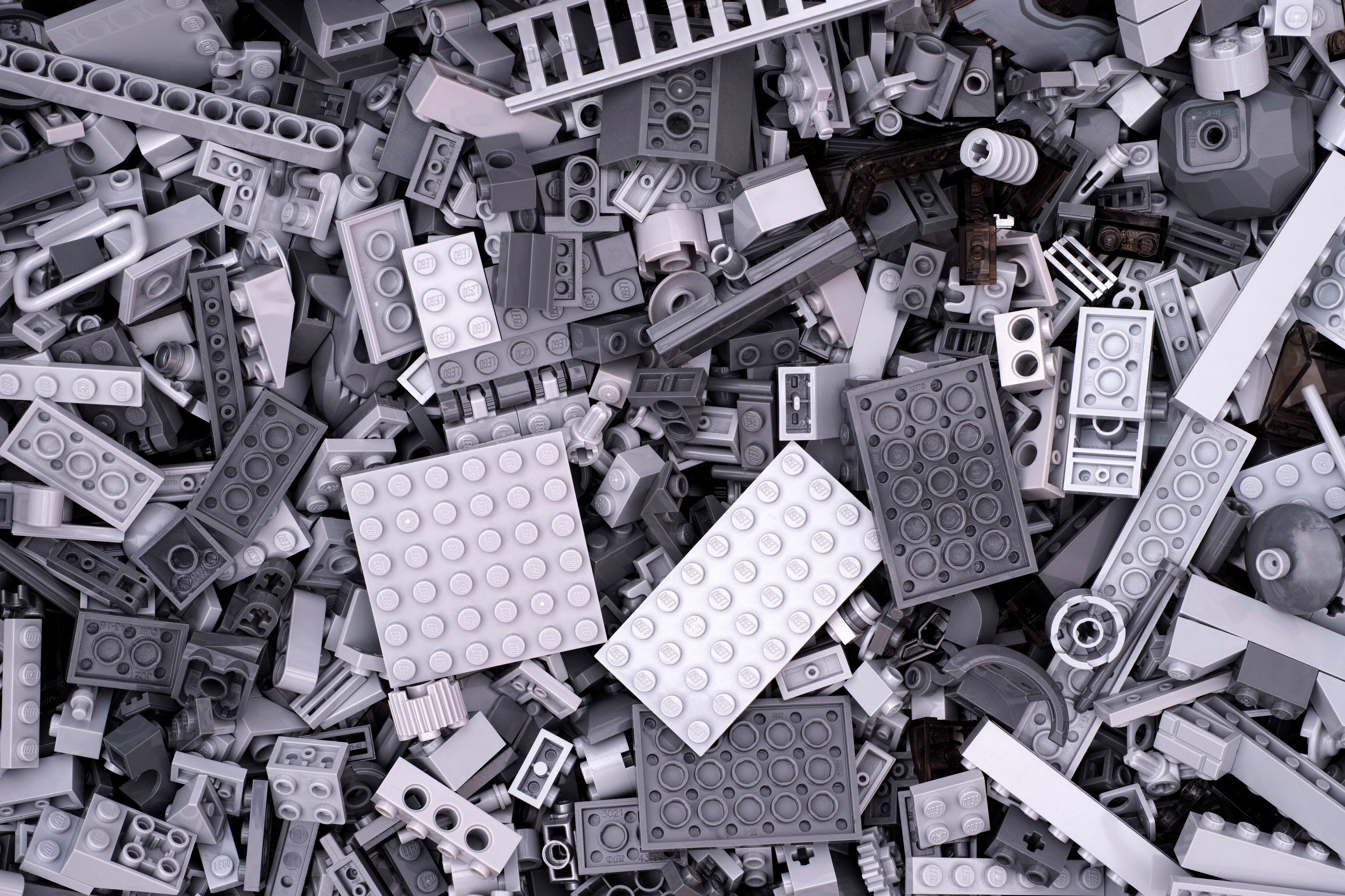 Photo en noir et blanc d’un amas désordonné de briques LEGO de formes et de tailles variées.