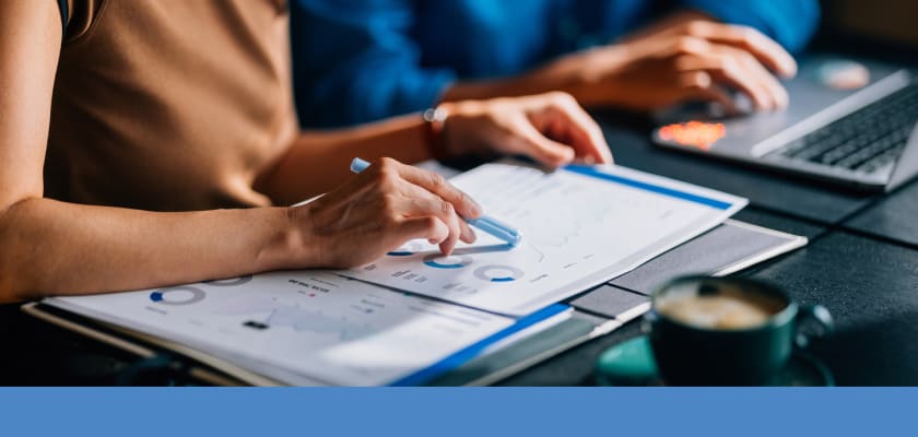 Woman tracing worksheets with graphs and charts using highlighter.