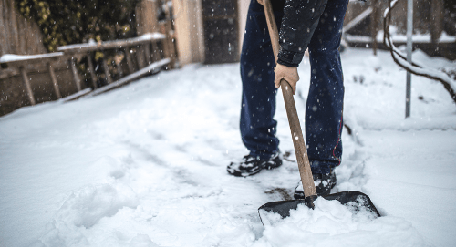 Man shoveling mixture of ice and snow in backyard