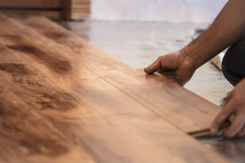Hands picking up floorboard in flooded room