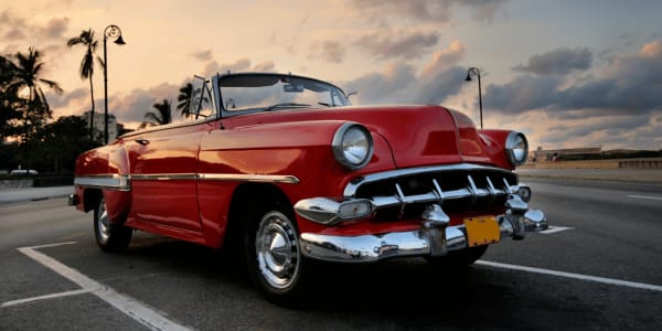 fast red classic car on road at sunset 