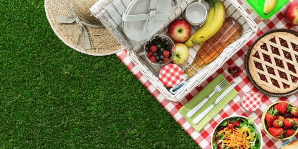 picnic basket and assorted foods on picnic blanket
