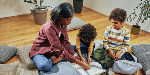 two children packing suitcase with mother