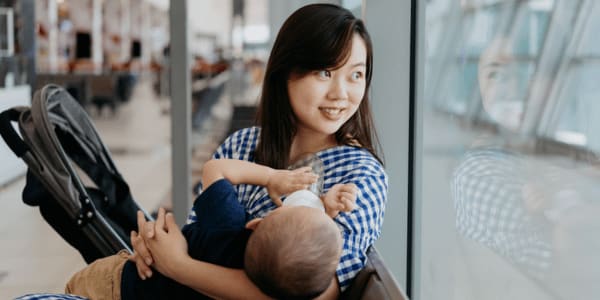 mother feeding baby a bottle at airport