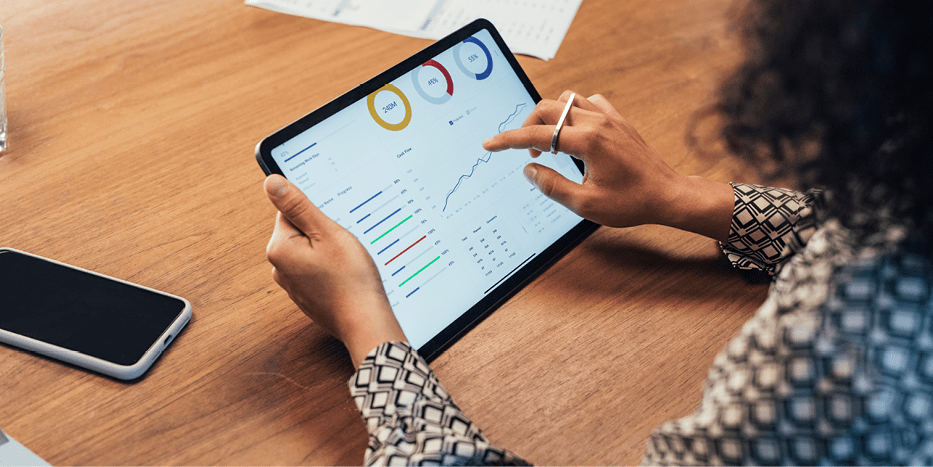 Woman holds tablet with slide of financial statistics, graphs, and charts on it.