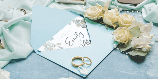 baby blue wedding invitation in envelope with gold rings on top