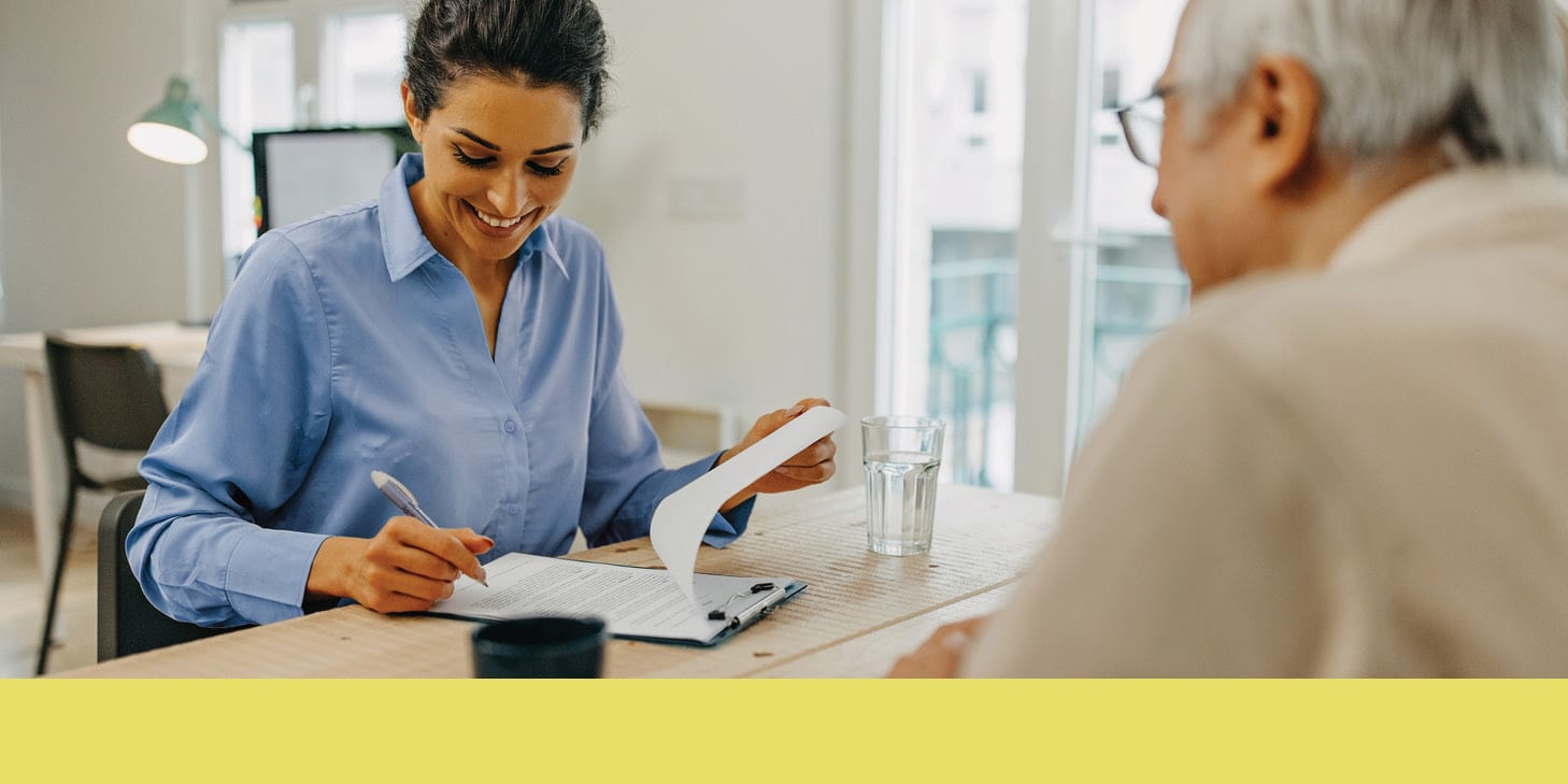 Woman taking notes on paper with a client seated opposite her