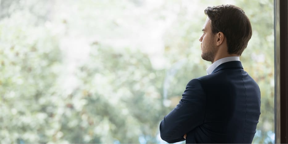 Professional man looking pensively outside a window