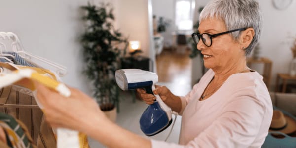 older woman steaming clothes for capsule wardrobe