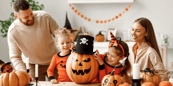 family of 4 celebrating halloween and carving pumpkins