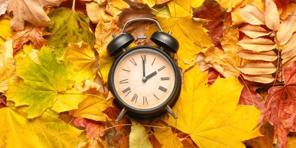 daylight savings clock on pile of fall leaves