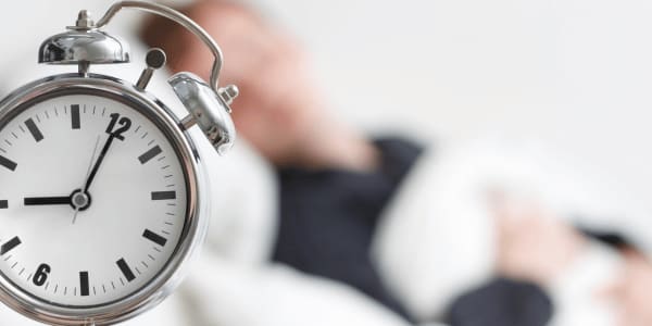 person sleeping with clock after daylight savings time