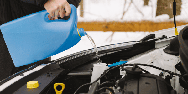 person refilling car windshield wipers in winter