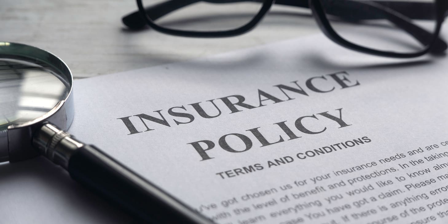 stack of papers that say insurance policy and eyeglasses