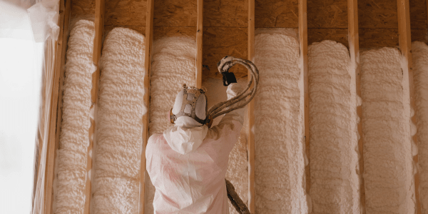 man in suit installing spray foam insulation