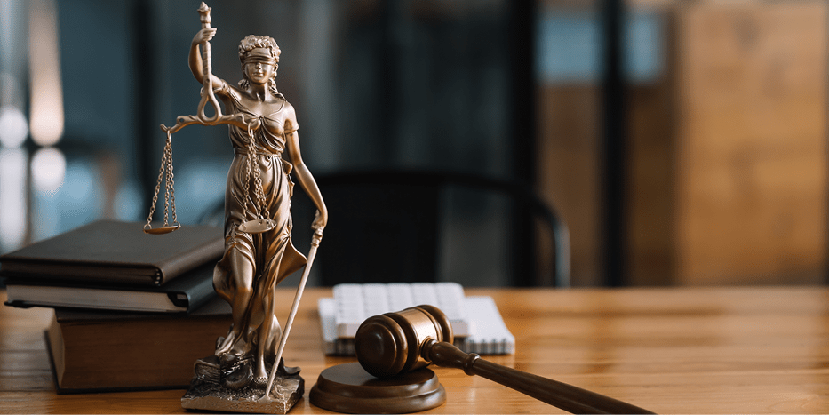 Lady justice statue with law books and documents on a table