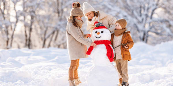 mother and two children building a snowman