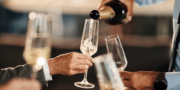waiter pouring sparkling wine in man's glass