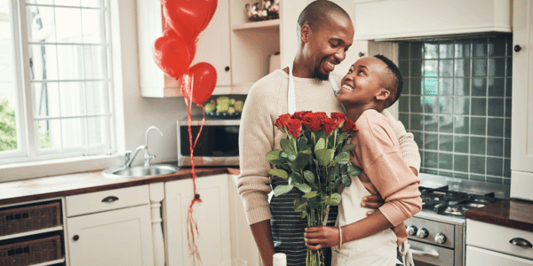 young couple celebrating valentine's day in kitchen with red roses