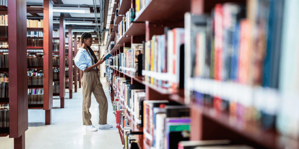 young woman checking out book from local library