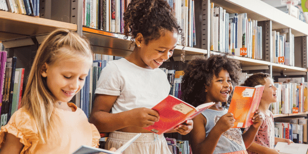 four young children reading books at local libary