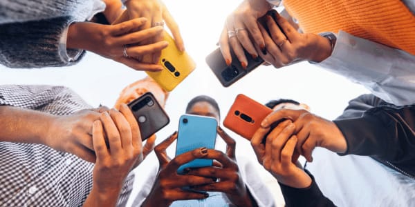teens standing in circle using smartphones