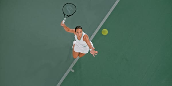 woman serving tennis ball on tennis court