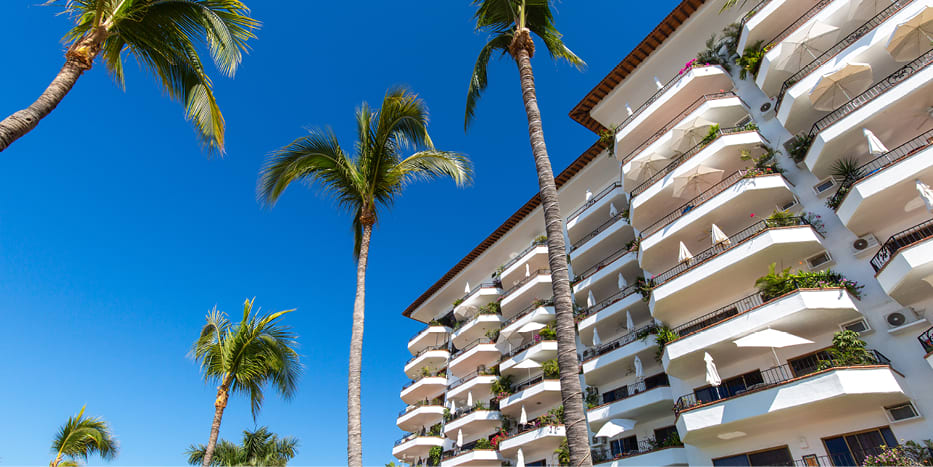 White condo building in Mexico surrounded by palm trees.