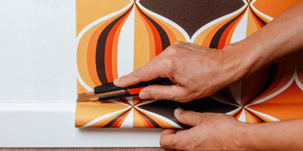 man cutting and installing wallpaper in home