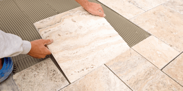 man installing natural stone tile in bathroom