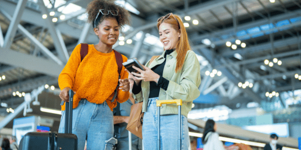 two female friends traveling with luggage at airport terminal