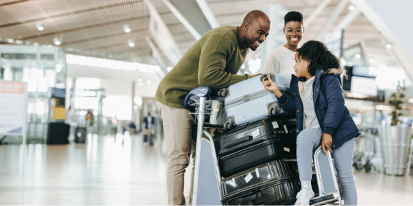 family traveling with stacked suitcases at airport