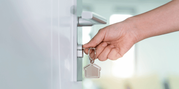 person locking door to home before leaving for vacation